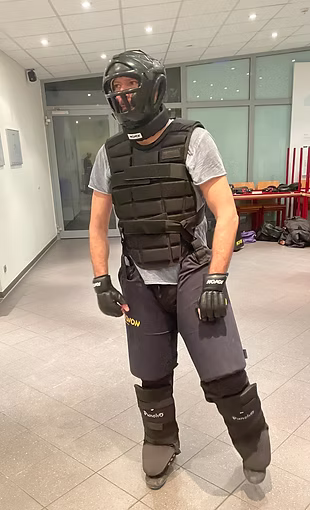 Kampfsportler trägt vollständige Schutzausrüstung, einschließlich Helm, Handschuhe und Schutzweste.